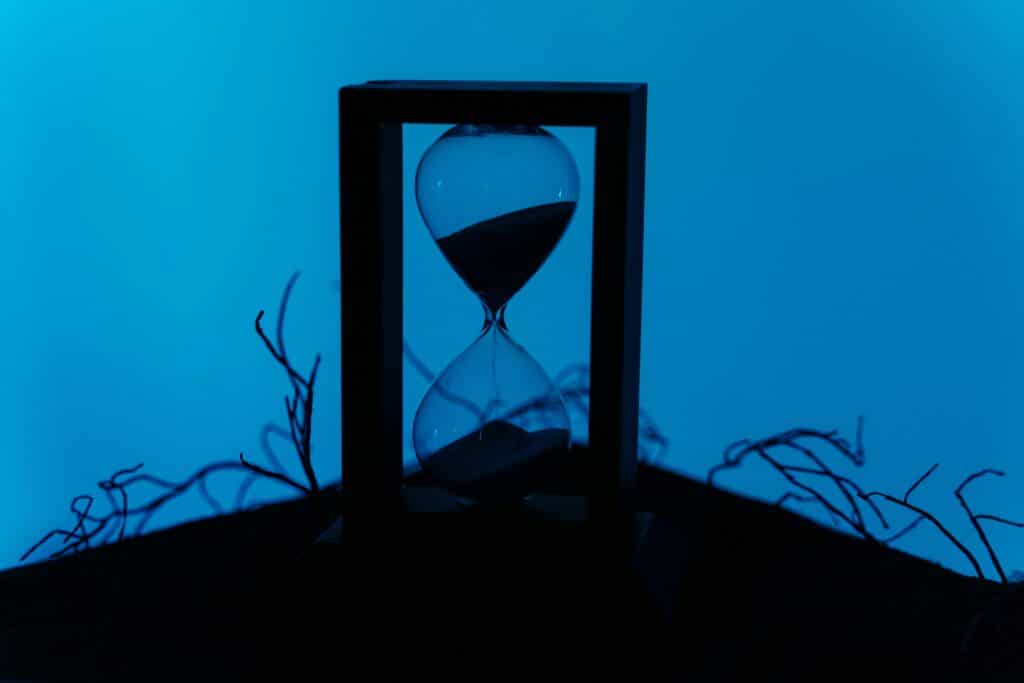 A silhouette of an hourglass set against a vivid blue background, highlighting the passage of time.